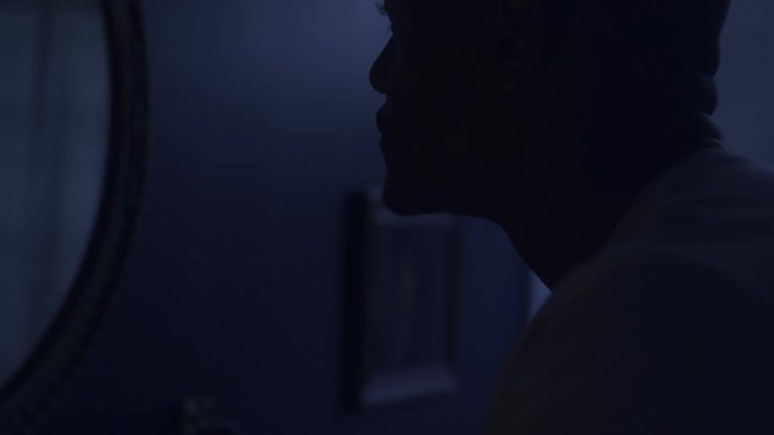 A man is looking in the mirror in his bathroom