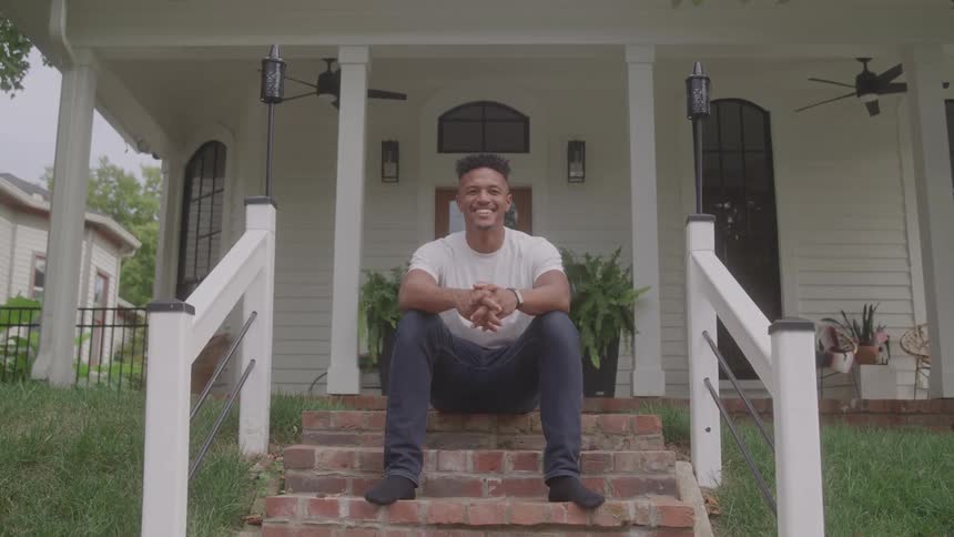 Happy man sitting on porch steps in front of his house
