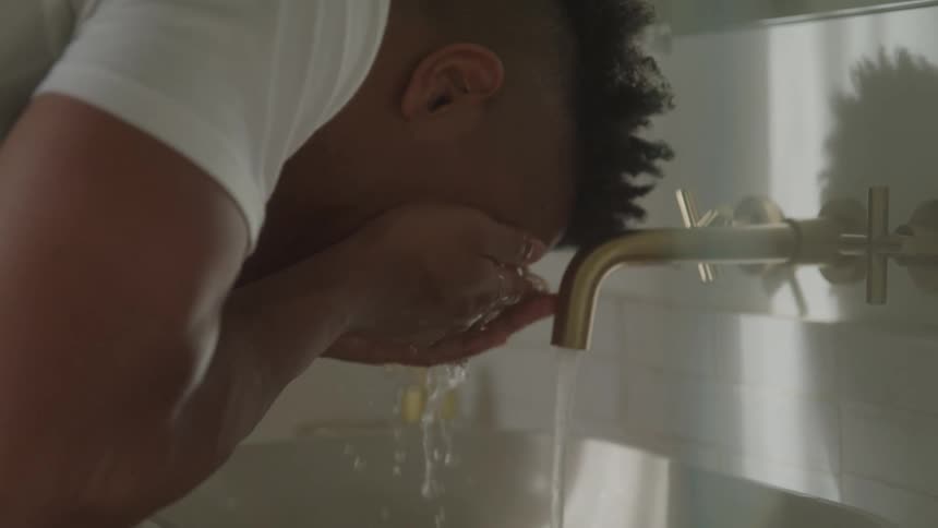 A man washing his face at a bathroom sink