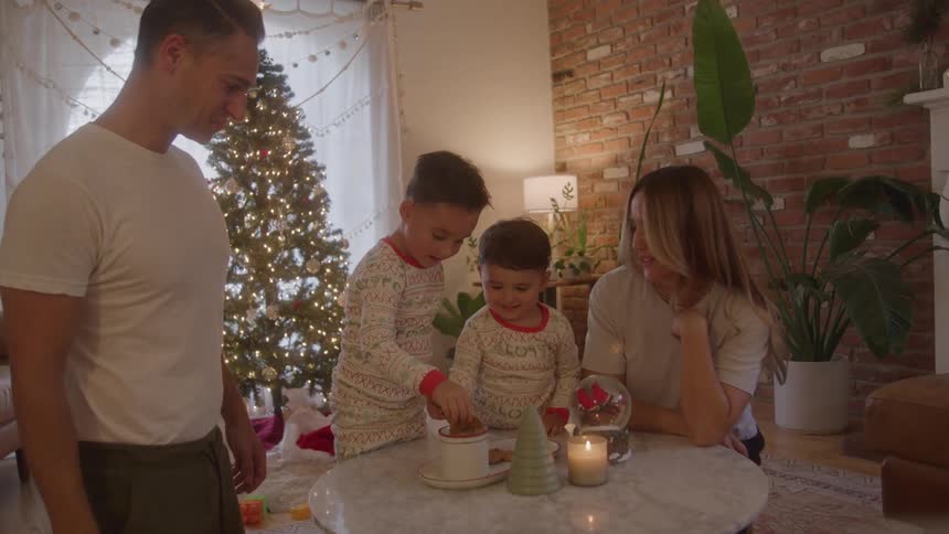 Family enjoys by christmas tree as kids eat treats