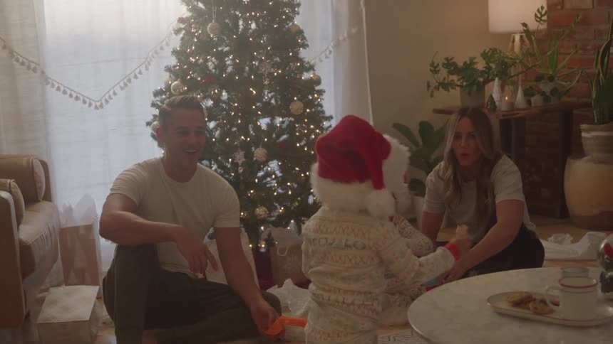 A family gathers by the christmas tree sharing joyful moments and cookies