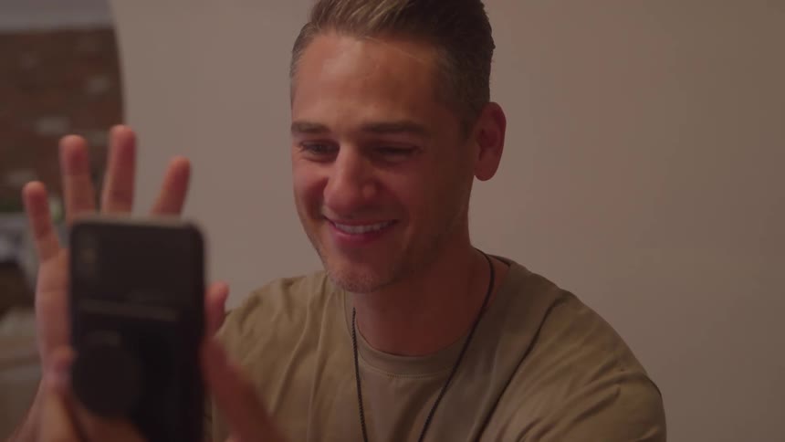 Happy man waving hello as he facetimes on his cell phone