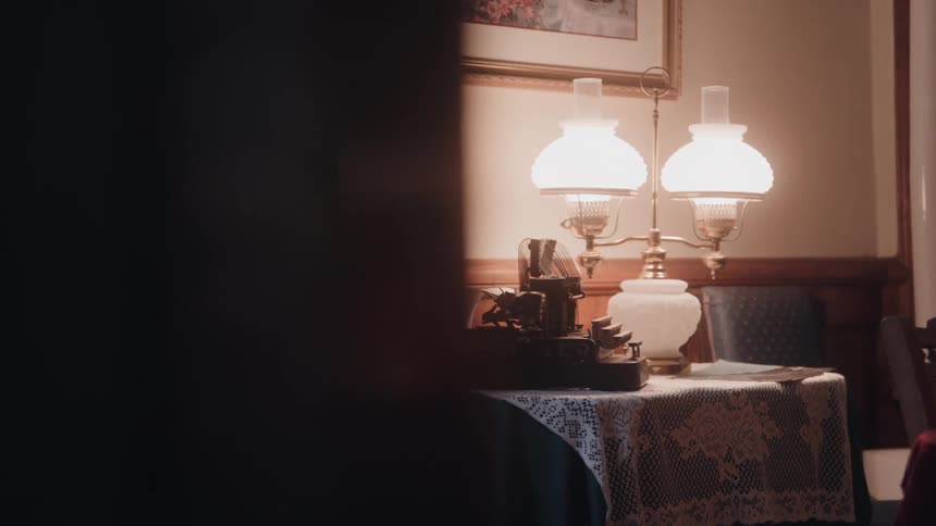 Table with lace cloth displays an old typewriter beside lit lamps