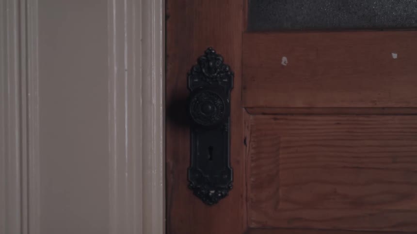 Partially open wooden door revealing a dark room