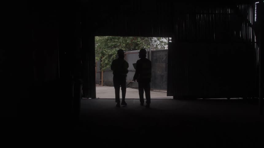 Two workers talk while exiting the warehouse