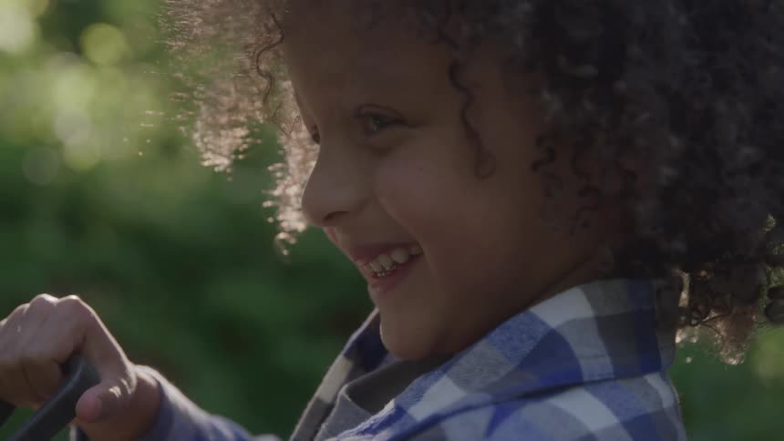 Child smiling while playing with a water hose