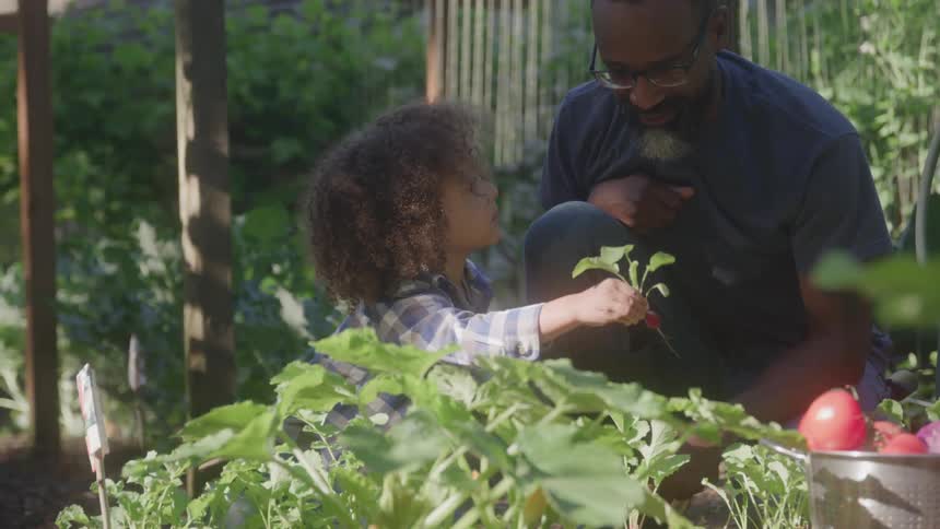 Man tends to child in a lush garden