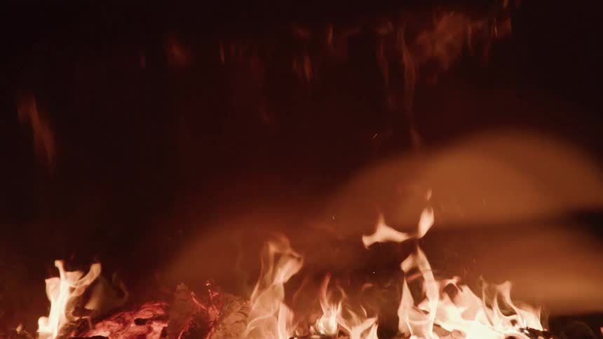 Logs of wood burn in a fire on an open field at night