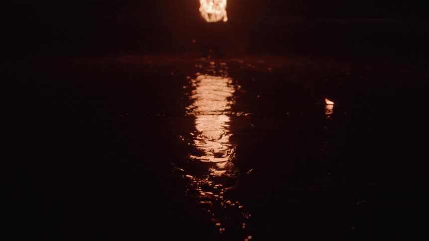 Reflection of flames lighting up the wet surface in the dark