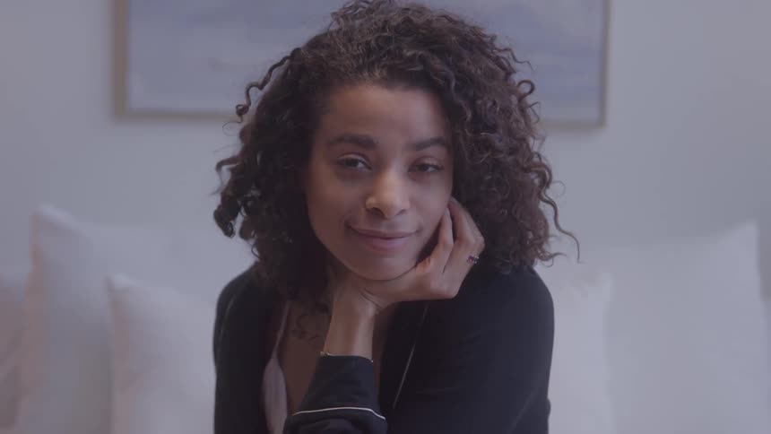 A young woman with curly hair smiles as she looks forward