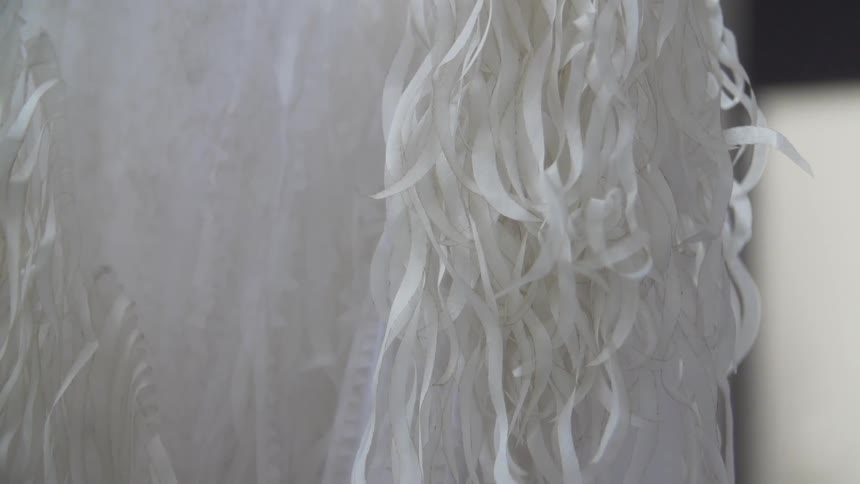 A large white piece of fabric with many white ribbons