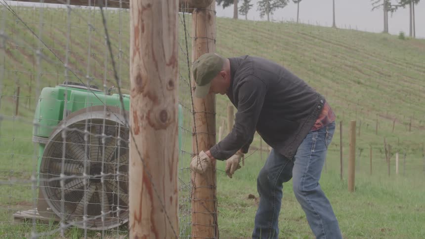 A farmer fixing fence at farm