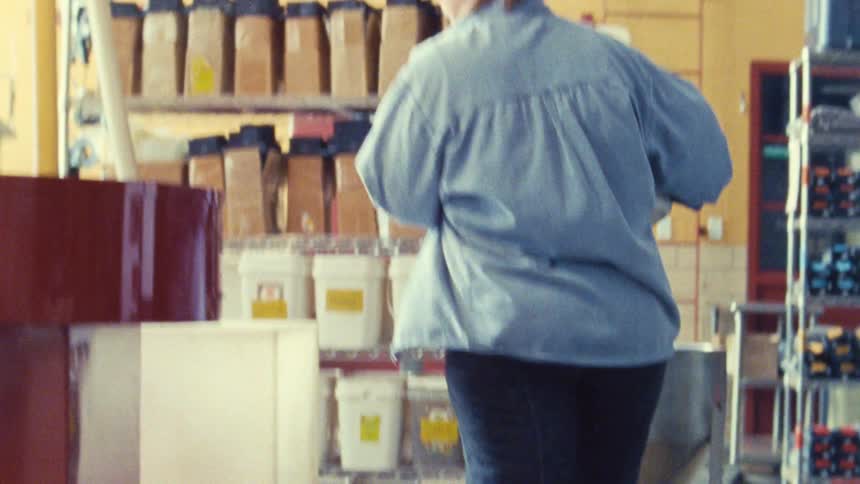 The woman empties a bucket of food into a machine