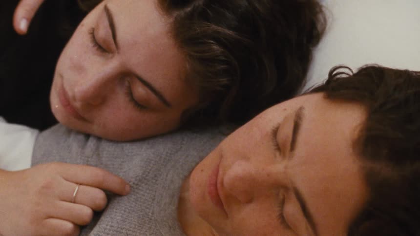 The video shows two people sleeping side by side on what appears to be a bed they are resting their heads against each other with their eyes closed suggesting an intimate and peaceful moment