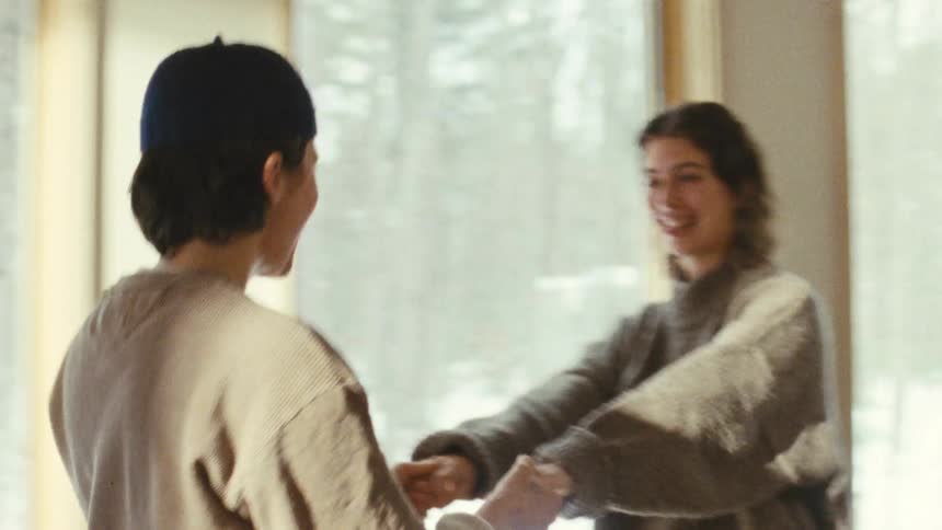 Close up of a young couple happily dancing together while holding hands in a room during daytime
