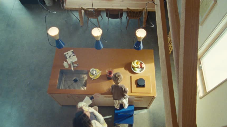 Woman makes coffee in kitchen as child watches