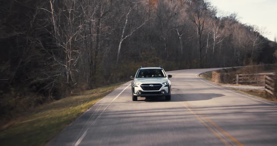 A car moving on a tarred road with trees on the side in the morning