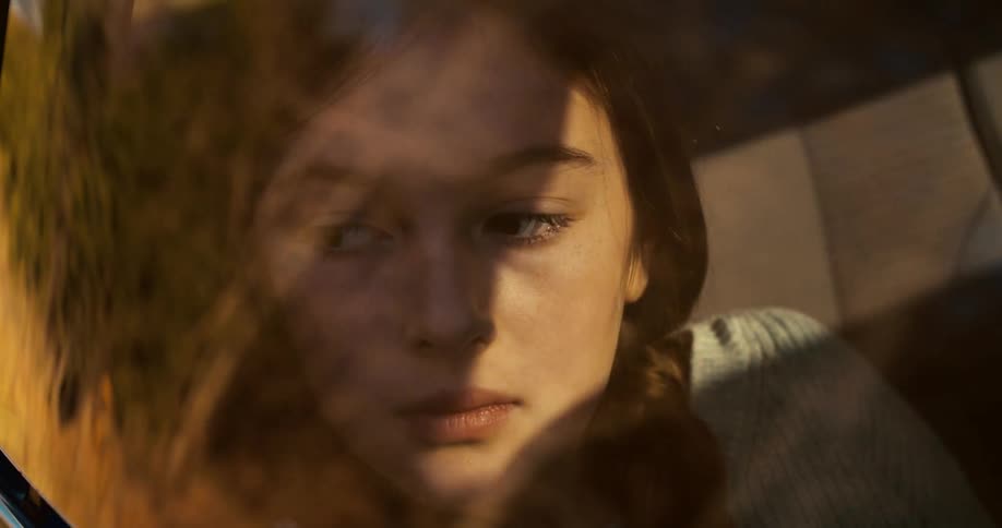 A sad looking woman in the passenger seat of a car her head leaning against the window during the drive