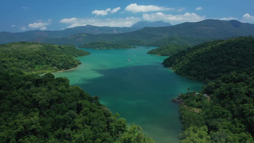 Aerial view of turquoise lake with green forest and mountains