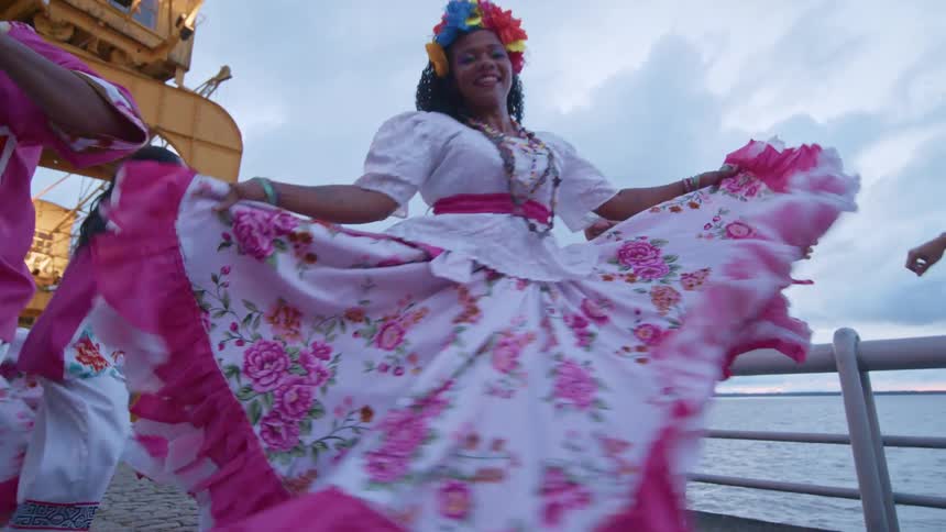 Six people men and women dancing happily on a bridge over the sea