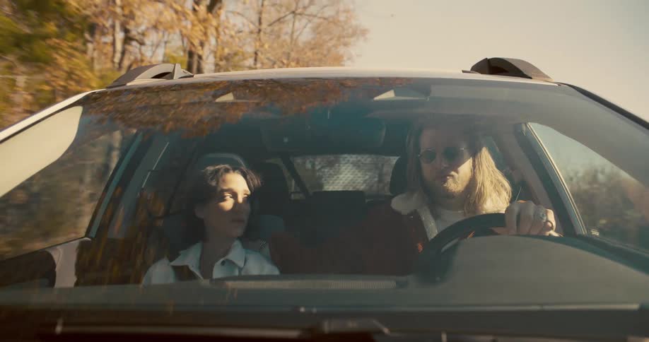 A man consoles a sad woman while they are driving