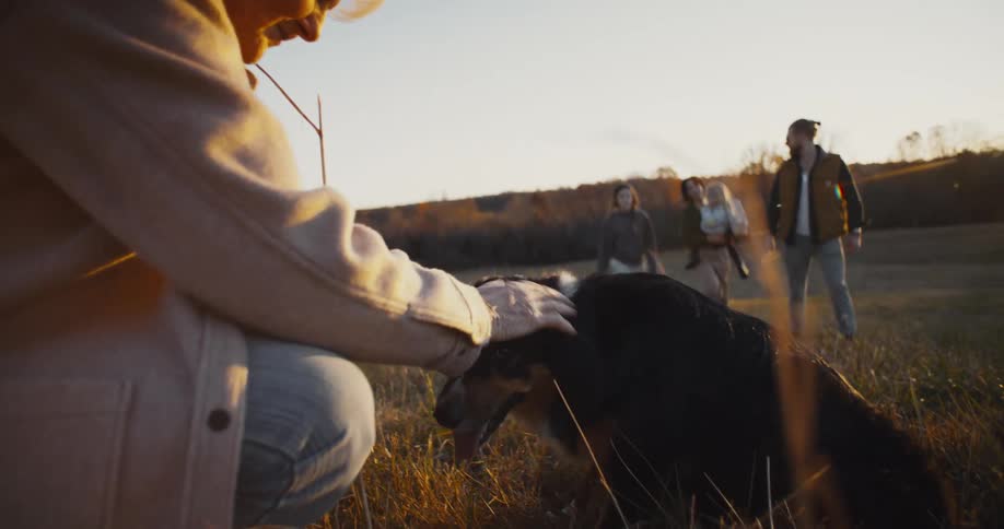 A family walks up to a woman petting her dog