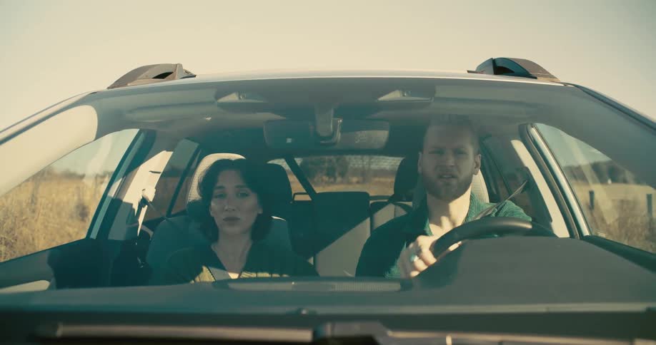 A woman and a man inside a car with the man driving