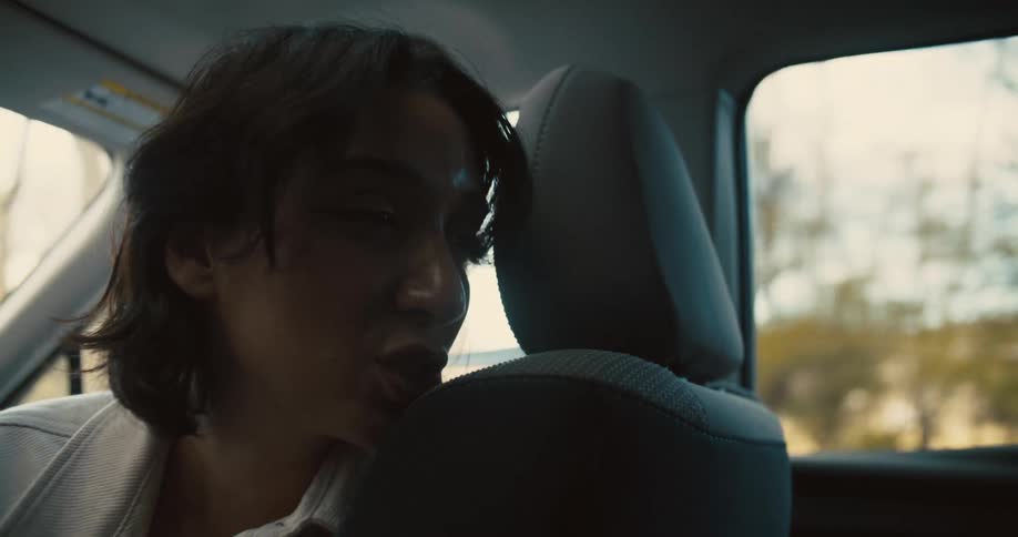 A woman talks with someone in the backseat on a car ride