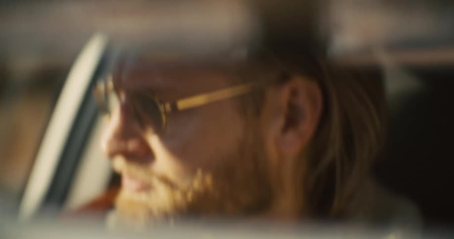 Man with sunglasses stares intently through the car window