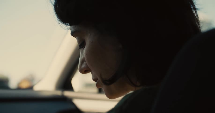The woman is looking down while going for a car ride