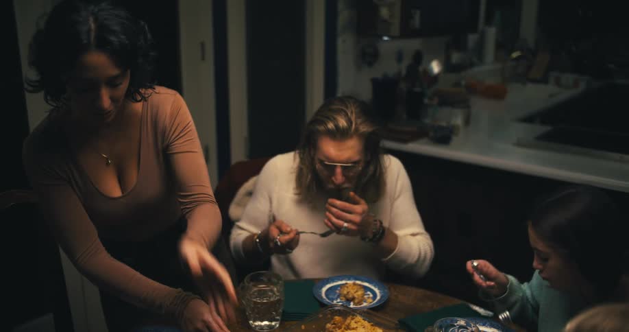 A family shares a dinner together at a dimly lit dining table