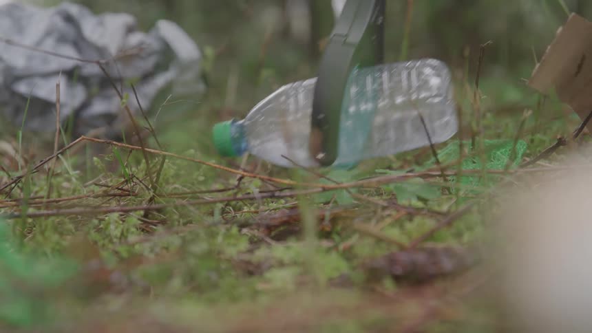 A litter picker grabs a plastic bottle from the ground