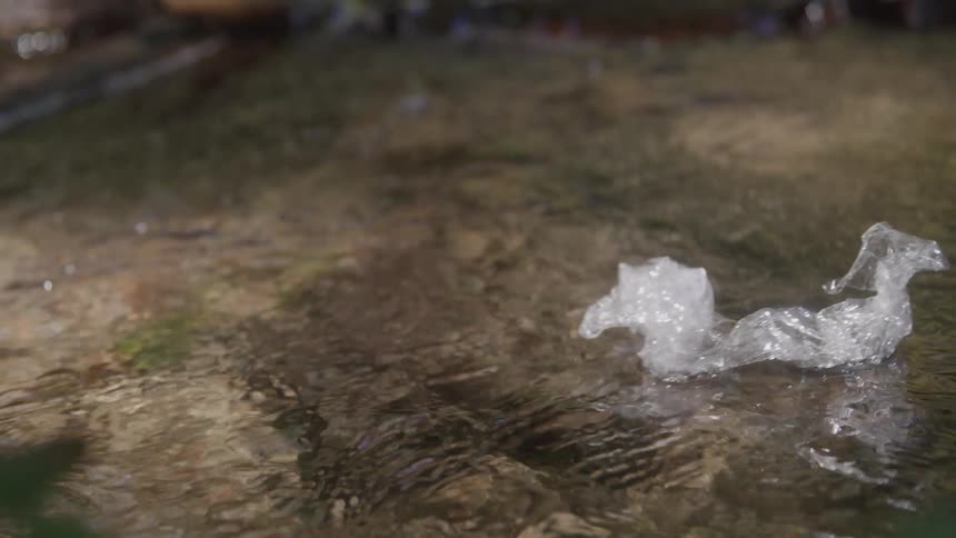 Piece of plastic floats on the water of a stream