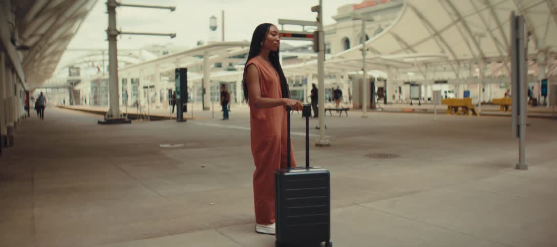 Woman with a suitcase standing in a covered train station