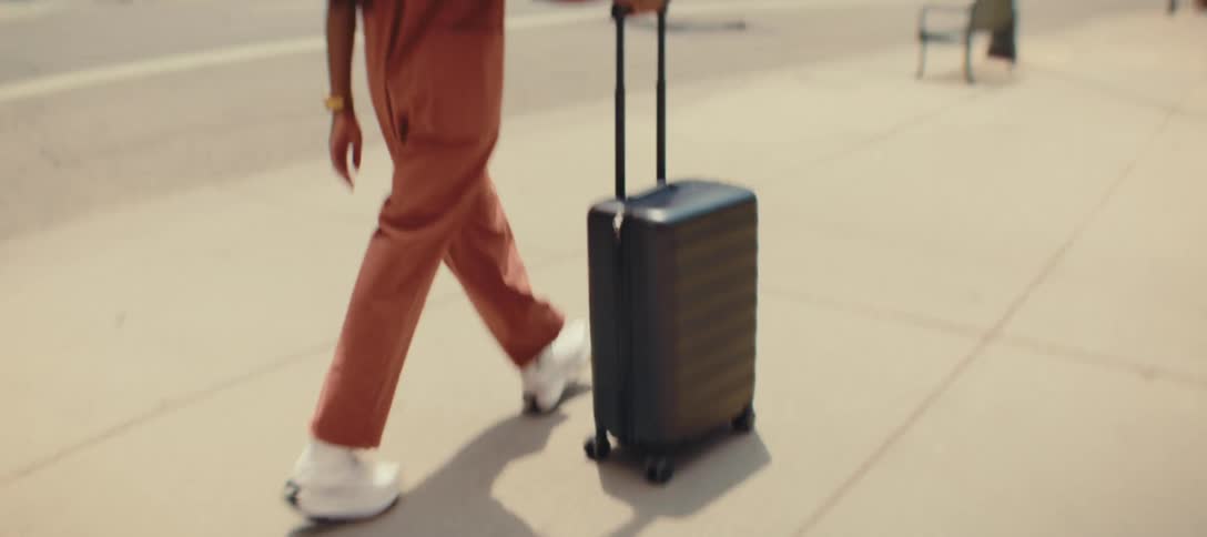 Woman pulls her luggage as she walks on a downtown sidewalk looking around