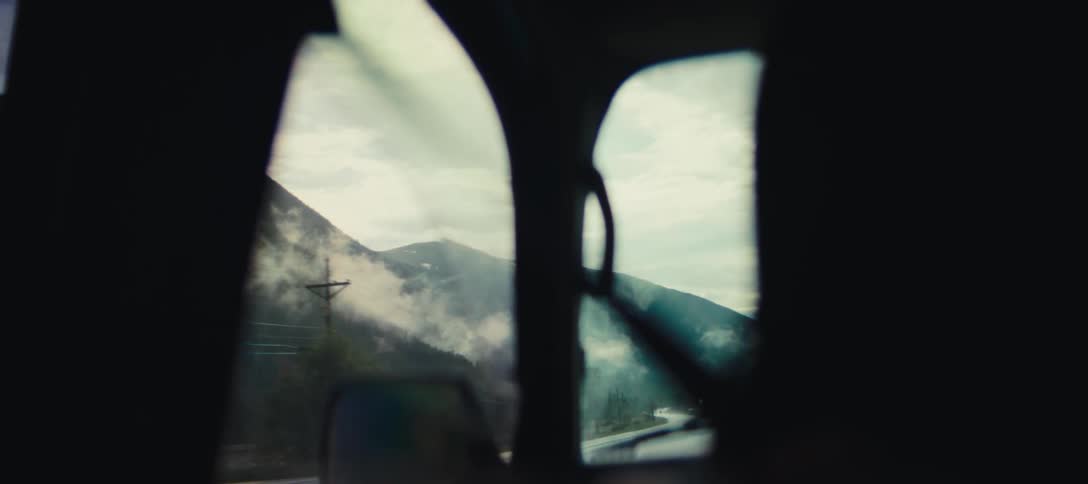 Road between misty mountains seen from inside a vehicle