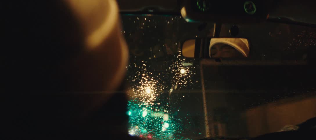 A woman driving a car down city streets in the rain