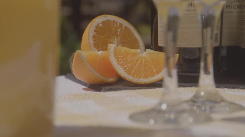 Orange slices beside glasses and bottles on the table