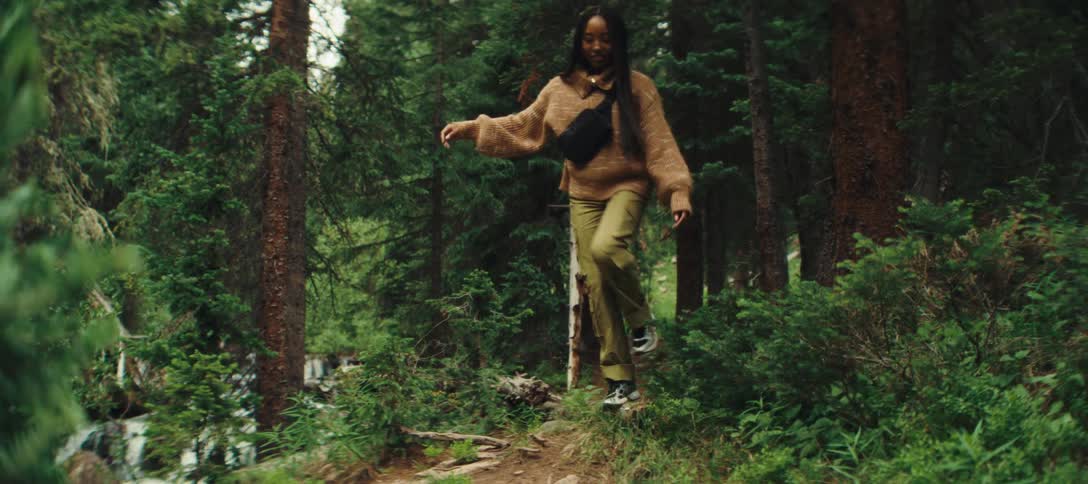 Awoman joyfully balancing on a forest trail