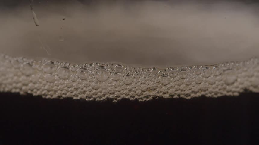 Bubbles from the carbonation sit atop the surface of a beverage