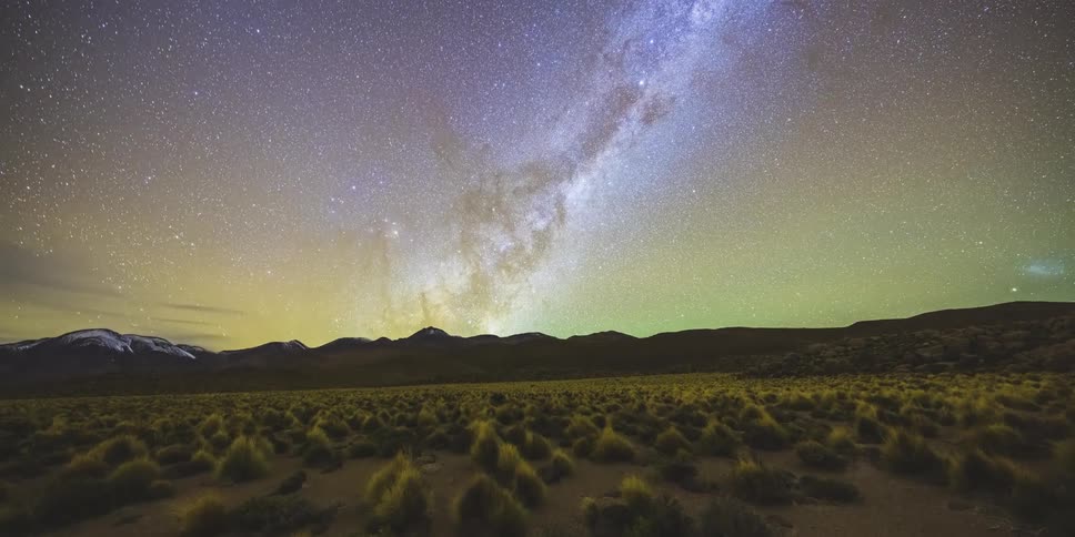 Stars of the milky way galaxy glow above desert mountains