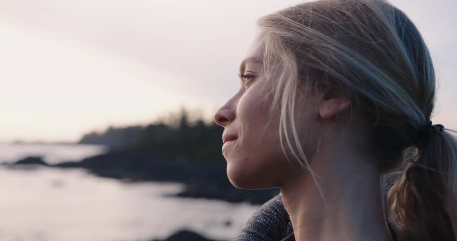 Blonde woman in profile looking at the horizon near the sea