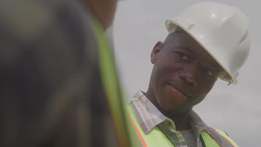 Worker in a hard hat and hivis vest confers on a job site
