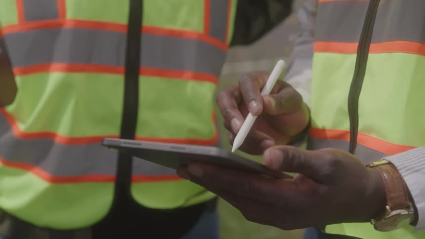 A worker writes on his tablet outside