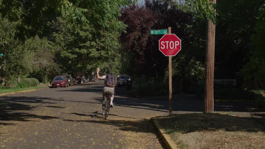 A young woman riding a bicycle passing by a stop sign