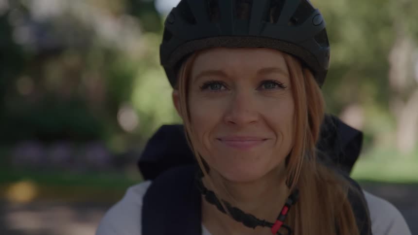 The woman on a bike smiles outside