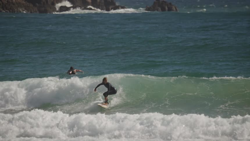 Surfers ride waves while others paddle in the ocean