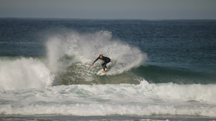 Surfer performs a maneuver on an open sea wave