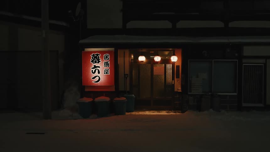 Illuminated facade of a japanese restaurant with a red sign and snow on the ground
