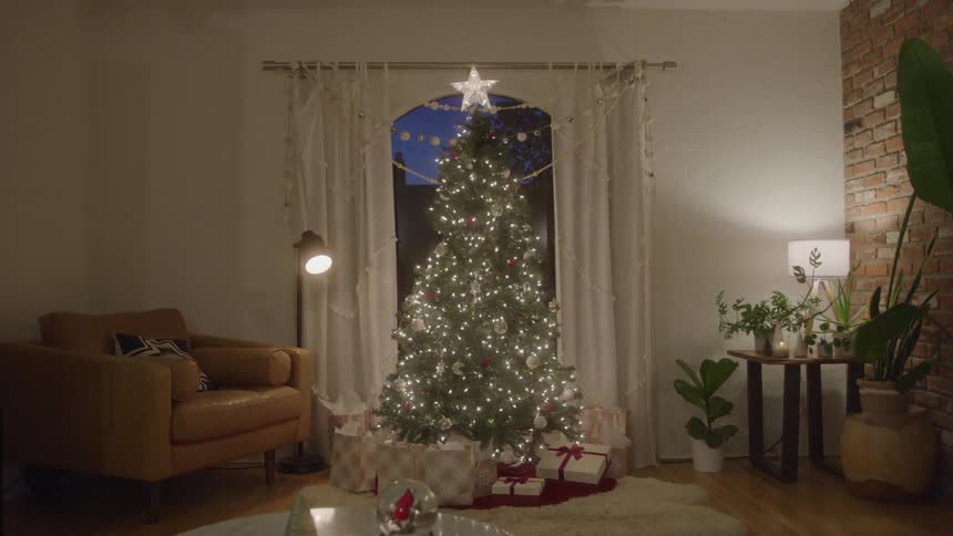 Living room decorated with a lit christmas tree and gifts around it
